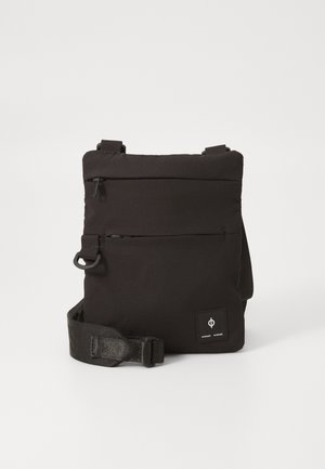 Kompaktne musta värvi crossbody kott, millel on reguleeritav rihm, kaks horisontaalset lukuga taskut ning väike brändi logo sildike esiküljel paremas alumises nurgas.