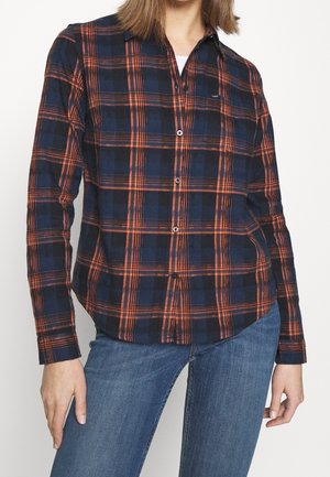 Chemise à boutons bleu marine et orange à carreaux, avec des manches longues et un ourlet incurvé. Fabriquée en tissu doux et léger.