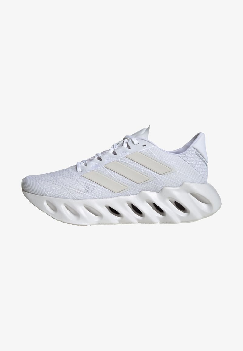White athletic shoe with a textured synthetic upper, three beige stripes on the side, and a chunky, sculpted white sole with ventilation cutouts.