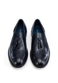 Black leather slip-on shoes with tassel detail, brogue perforations, rounded toe, and a smooth finish, featuring a contrasting blue interior.