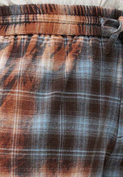 Καφέ και μπλε καρό ύφασμα με ελαστική ζώνη και κορδόνι σε ένα παντελόνι ή σορτς.