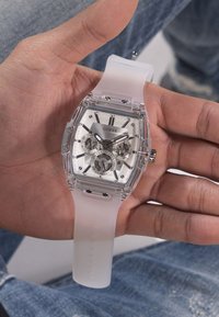 Orologio in plastica trasparente con cinturino in silicone bianco, cassa rettangolare, dettagli in argento, grande quadrante bianco e tre sottodial per funzioni cronografiche.