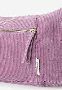 Paarse ribfluwelen tas met een gouden rits, gestructureerd ribbeloppervlak en een label met "Sissy-Boy" branding.