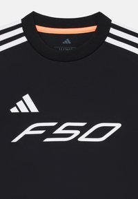 Fekete sporting póló fehér "F50" logóval és három fehér csíkkal a vállakon, narancssárga kiemeléssel a galléron.