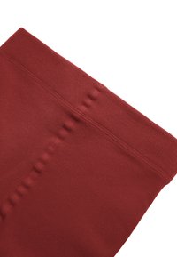 Leggings rojos elásticos que cuentan con una cinturilla ancha y una textura suave, con detalles de costura sutiles a lo largo de los lados.