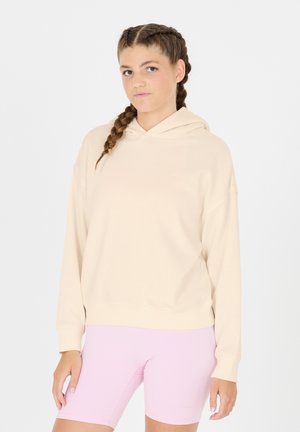 Cremefarvet hoodie lavet af blødt stof, har hætte og sænkede skuldrer. Blevet parret med lyserøde kompressionsshorts. Enkel design.