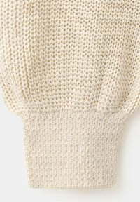 Manica di maglione lavorato a maglia di colore crema con polsino a coste e motivo a punto strutturato sopra il polsino.