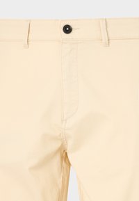 Beige katoenen broek met een rechte snit, voorzien van een enkele zwarte knop bij de tailleband en subtiele stikdetails.