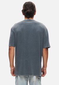 Grå kortärmad t-shirt, avslappnad passform, tillverkad av mjukt bomullstyg, med rundad halsringning och en enkel baksida utan utsmyckningar.