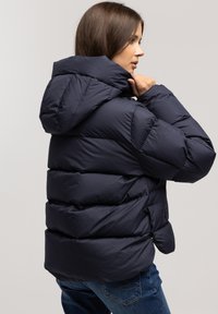 Kurtka puchowa w granatowym kolorze z kapturem, z pikowanym wzorem, poziomymi przeszyciami i lekko skróconym fasonem.
