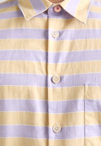 Chemise à col avec des rayures horizontales jaunes et violet clair, boutonnée avec quatre boutons.