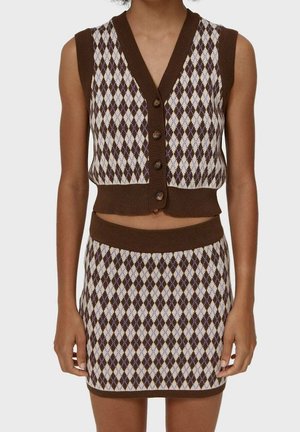Sleeveless brown and beige argyle knit vest with buttons paired with matching high-waist argyle knit mini skirt on a standing person.