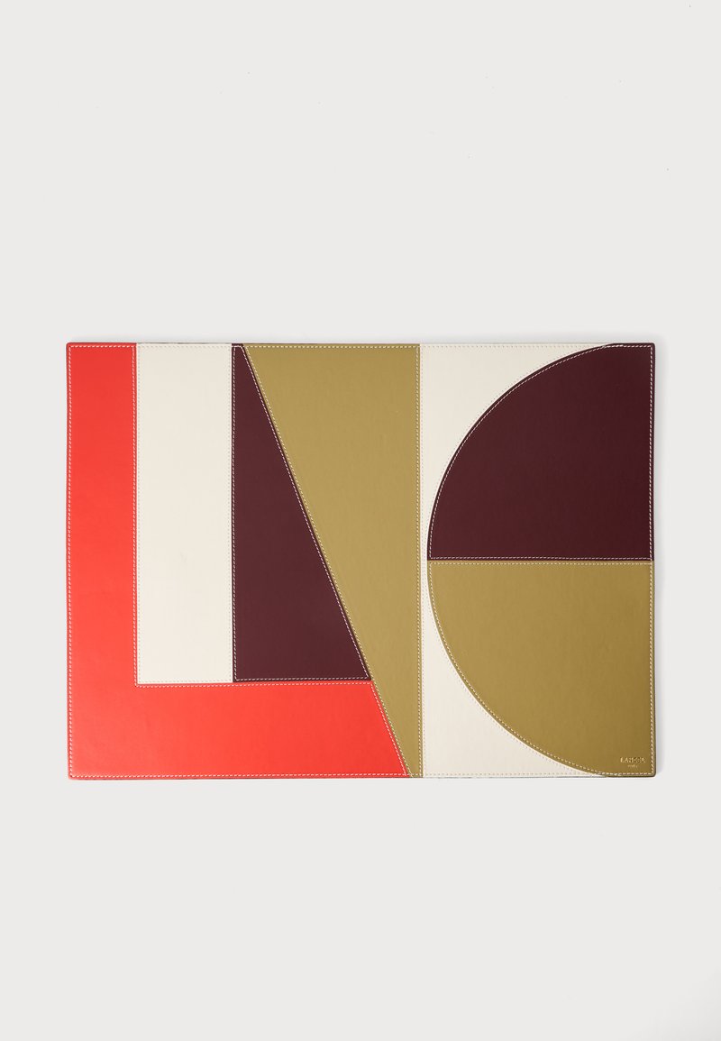 Set de table rectangulaire avec des blocs de couleur géométriques en rouge, crème, vert olive et brun foncé cousus ensemble en formes abstraites.