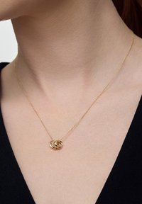 Złoty naszyjnik z trzema splecionymi pierścieniami na delikatnym łańcuszku. Pierścienie mają gładkie wykończenie z subtelną teksturą.