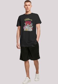 Black cotton t-shirt featuring a colorful "Alice in Wonderland" graphic print. Short sleeves, classic round neckline, relaxed fit.