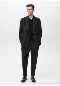 Black double-breasted suit jacket with a textured black sweater, paired with tapered black trousers and glossy black loafers.