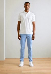 Hvid polo skjorte med korte ærmer, lyseblå bukser og hvide sneakers. Alsidig pasform, glat tekstur og minimalistisk design.