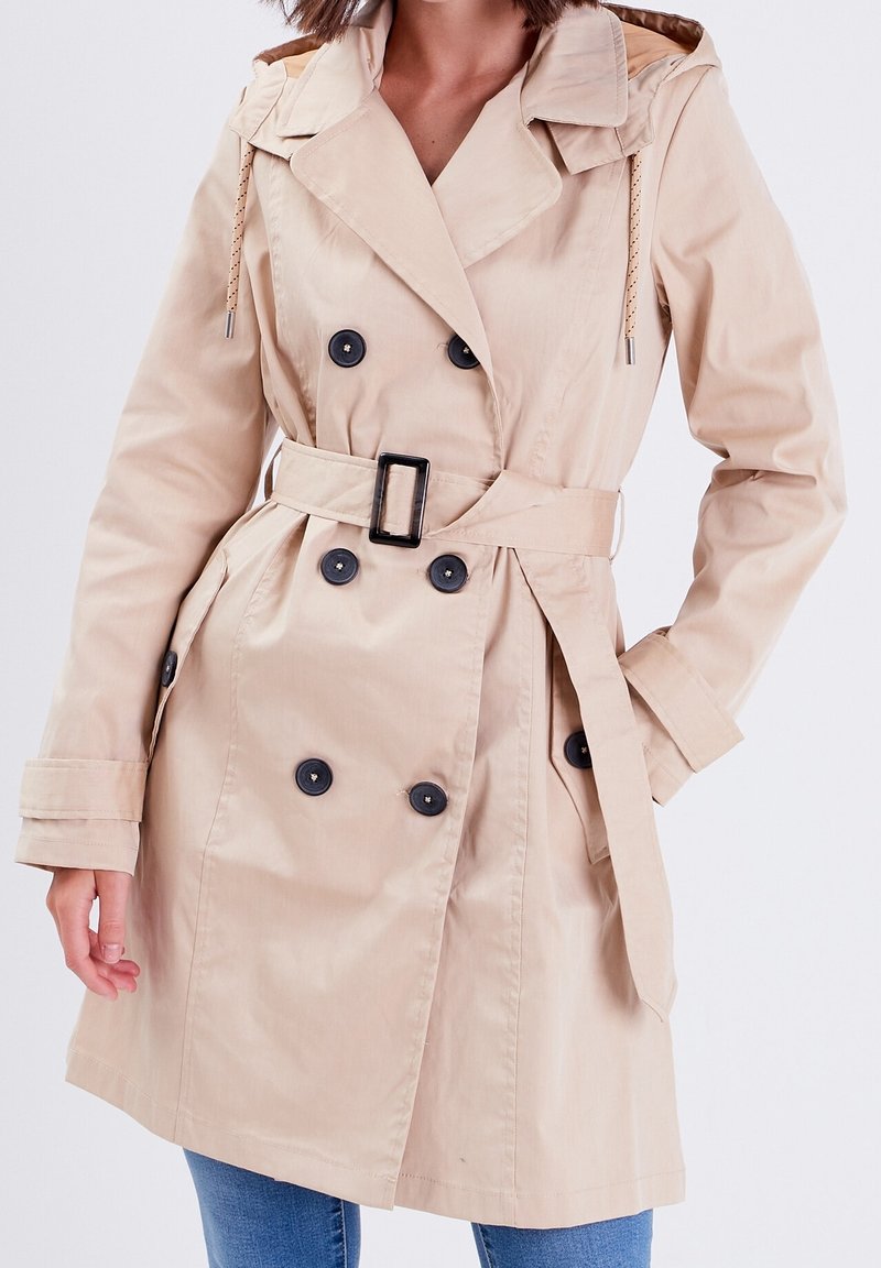 Beige trenchcoat met een ceintuur in de taille, dubbel-gestulpte ontwerp, donkere knopen en capuchon. Gemaakt van een soepele stof met een duurzame afwerking.