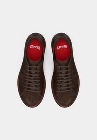 Zapatillas de cuero marrón con textura suave, punta redonda y suela de goma. En el interior tienen plantillas rojas con el logo "CAMPER" en blanco.