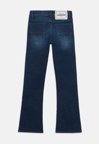 Jean évasé bleu foncé avec une texture en denim, doté d'une étiquette de marque sur la ceinture arrière et de deux poches arrière.