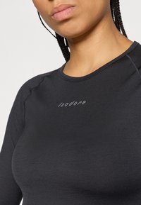 Musta pitkähihainen paita, jossa on sileä pinta ja ommeltu sauma. "Isadore"-logo vaaleanharmaana edessä, pyöreä kaula-aukko.