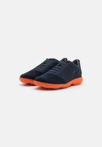 Navy suede shoes with a smooth upper and textured sole; features orange accents on the sole and a lace-up design for secure fit.
