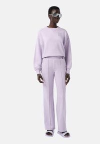 Lila kleurige sweatshirt met een ronde halslijn en gathered mouwen, gecombineerd met bijpassende geplisseerde broeken en pluche slippers.