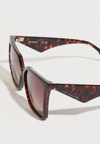 Gafas de sol con montura geométrica de carey, lentes marrones degradados, detalles metálicos y la marca Karl Lagerfeld en la patilla.