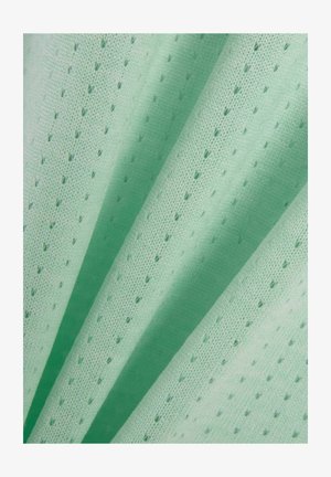 Lichtgroene stof met kleine, gelijkmatig verdeelde perforaties, getoond in zachte plooien die de textuur en ademend materiaal benadrukken.