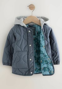 Veste rembourrée marine avec une capuche grise. L'intérieur présente une doublure bleu clair avec des motifs d'éléphant. Comprend des fermetures à pression et une poche avant.