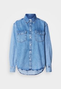 Chemise en denim bleu clair à manches longues avec col pointu, boutons-pression sur le devant, deux poches poitrine à rabats et ourlet arrondi.