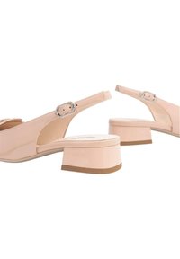 Scarpe slingback in pelle verniciata beige con punta tonda, fibbia regolabile e tacco a blocco basso. Suola testurizzata per una buona aderenza.