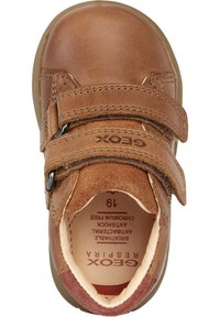 Zapato de cuero marrón con dos correas de velcro ajustables, punta redonda y suela de goma. El interior cuenta con una forro transpirable y plantillas.