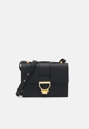 Zwarte leren crossbody tas met een gestructureerde afwerking, gouden hardware en een klep sluiting met een opvallende ronde accent.