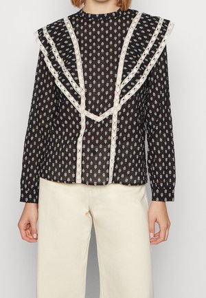 Zwarte doorschijnende blouse met lange mouwen, witte bloemenprint en crèmekleurige kanten rand, gedragen met hooggetailleerde off-white broek.