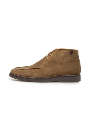 Brauner Wildleder-Schnürstiefel mit dunkler Gummisohle und minimalen Nähten, von der Seite auf weißem Hintergrund betrachtet.