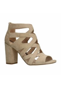 Beige suède sandalen met hak, voorzien van meerdere uitgesneden banden en een open teen ontwerp. De blokhak biedt stabiliteit en hoogte.