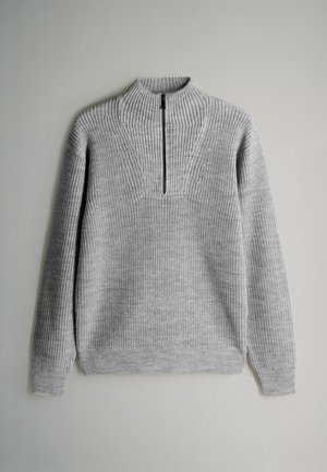 Šedý pletený svetr s vysokým límcem, který má zapínání na půl zip a žebrovanou texturu. Dlouhé rukávy a uvolněný střih.