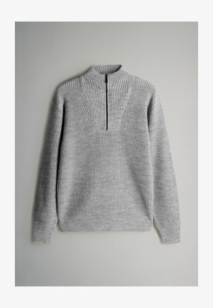 Šedý pletený svetr s vysokým límcem, který má zapínání na půl zip a žebrovanou texturu. Dlouhé rukávy a uvolněný střih.