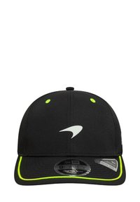 Czarna czapka z zakrzywionym daszkiem, wykonana z materiału. Posiada białe logo oraz neonowe zielone akcenty wzdłuż daszka. Widoczny regulowany rozmiar.