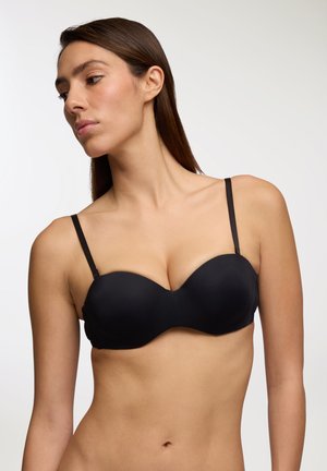Reggiseno push-up nero con coppe morbide e sagomate, spalline sottili e regolabili, e un design senza cuciture, creando una silhouette strutturata.