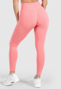 Collant a vita alta di un vivace colore rosa, con una texture liscia e un sottile motivo a diamante sui polpacci. Abbinate a sneakers bianche.