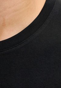 Sort bomulds t-shirt med rund hals, der har en ribbet krave og glat tekstur, vist i et nærbillede.