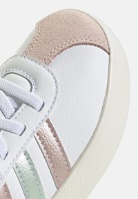 Baskets blanches avec des accents texturés rose et vert menthe, tige en cuir, patch en daim et lacets blancs. Détails cousus remarquables sur les côtés.
