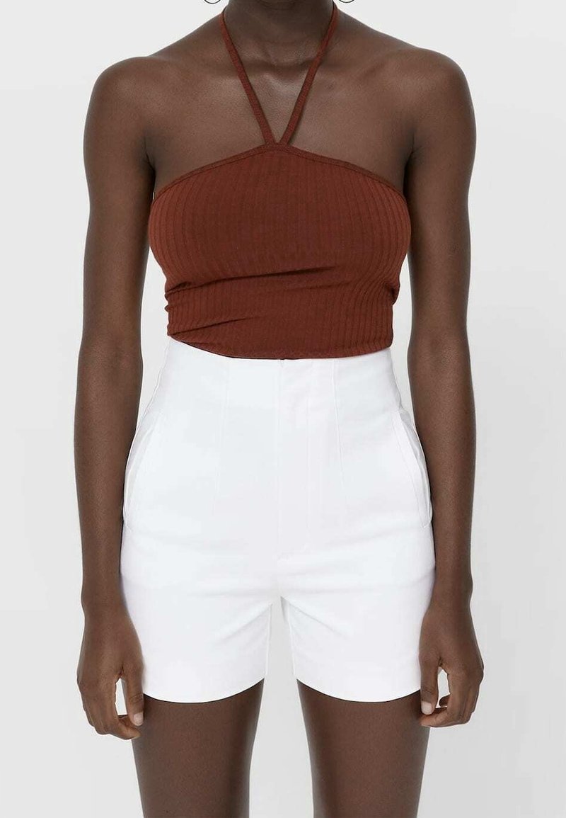 Bruine geribde crop top met dunne bandjes, gecombineerd met witte high-waisted shorts. De outfit heeft een aansluitend ontwerp en een gladde textuur.