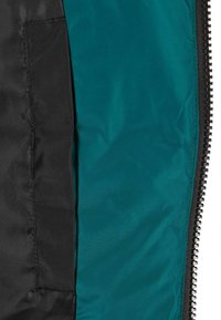 Wnętrze kurtki w kolorze czarnym i turkusowym z widocznym zamkiem błyskawicznym wzdłuż krawędzi, gładką fakturą oraz kieszenią po lewej stronie.