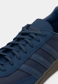 Μπλε αθλητικά παπούτσια με σχεδιασμό από σουέτ και δίχτυ, που διαθέτουν υφασμένες κορδόνια και τρεις οριζόντιες ρίγες. Παχιά, υφασμένη σόλα από καουτσούκ.