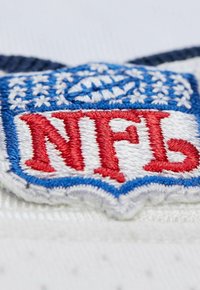 NFL-Logo-Patch mit roten gestickten Buchstaben auf weißem Hintergrund, eingerahmt von blauen und weißen Akzenten sowie einem strukturierten Stoffrand.