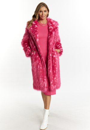 Roze nepbontjas met gemarmerd patroon, knielang, oversized design, twee voorzakken, gelaagd over een aansluitende roze jurk en witte laarzen.