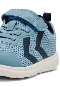 Jasnoniebieski but sportowy z siateczkową cholewką, niebieskimi akcentami, wyściełanym językiem i regulowanym paskiem. Teksturowana biała gumowa podeszwa z wzorem zapewniającym przyczepność.